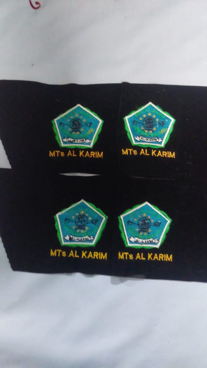 Empat contoh emblem berbentuk perisai dengan gambar dan tulisan pada kain gelap
