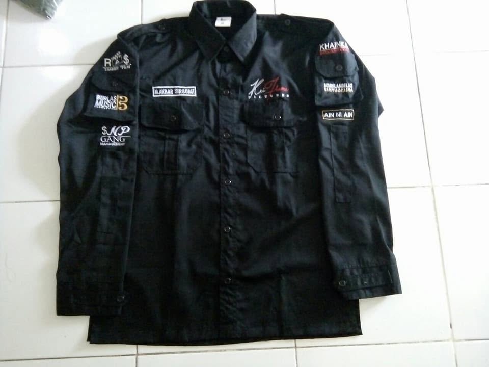 Kemeja hitam lengan panjang dengan tulisan dan logo pada dada serta lengan