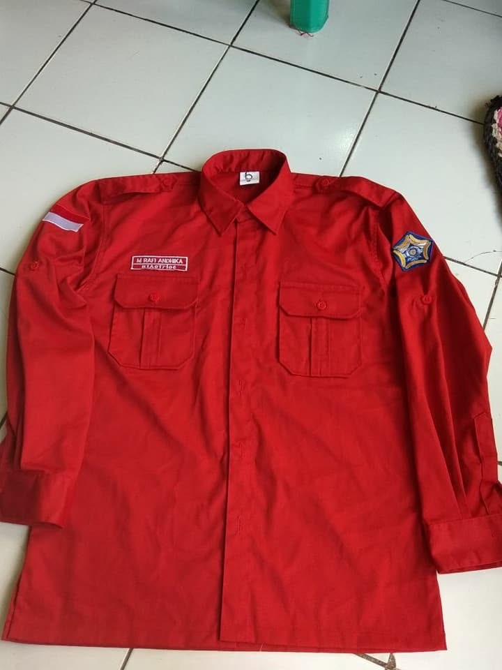 Kemeja merah lengan panjang dengan dua saku dada bertutup dan detail pada lengan