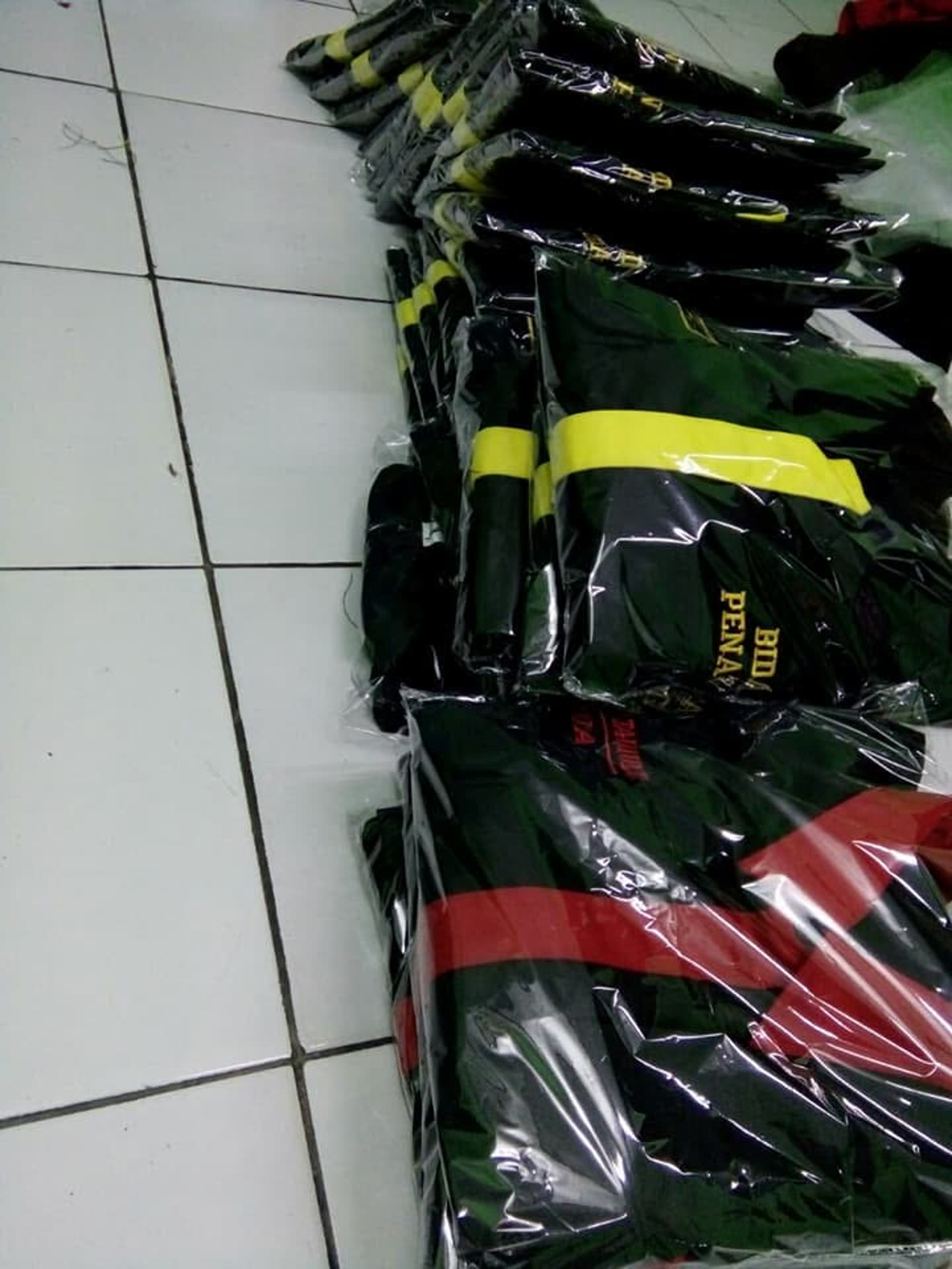 Tumpukan produk pakaian; sebagian terbungkus plastik. Jumlah pesanan dan kesiapan kirim tidak dapat dipastikan dari foto.