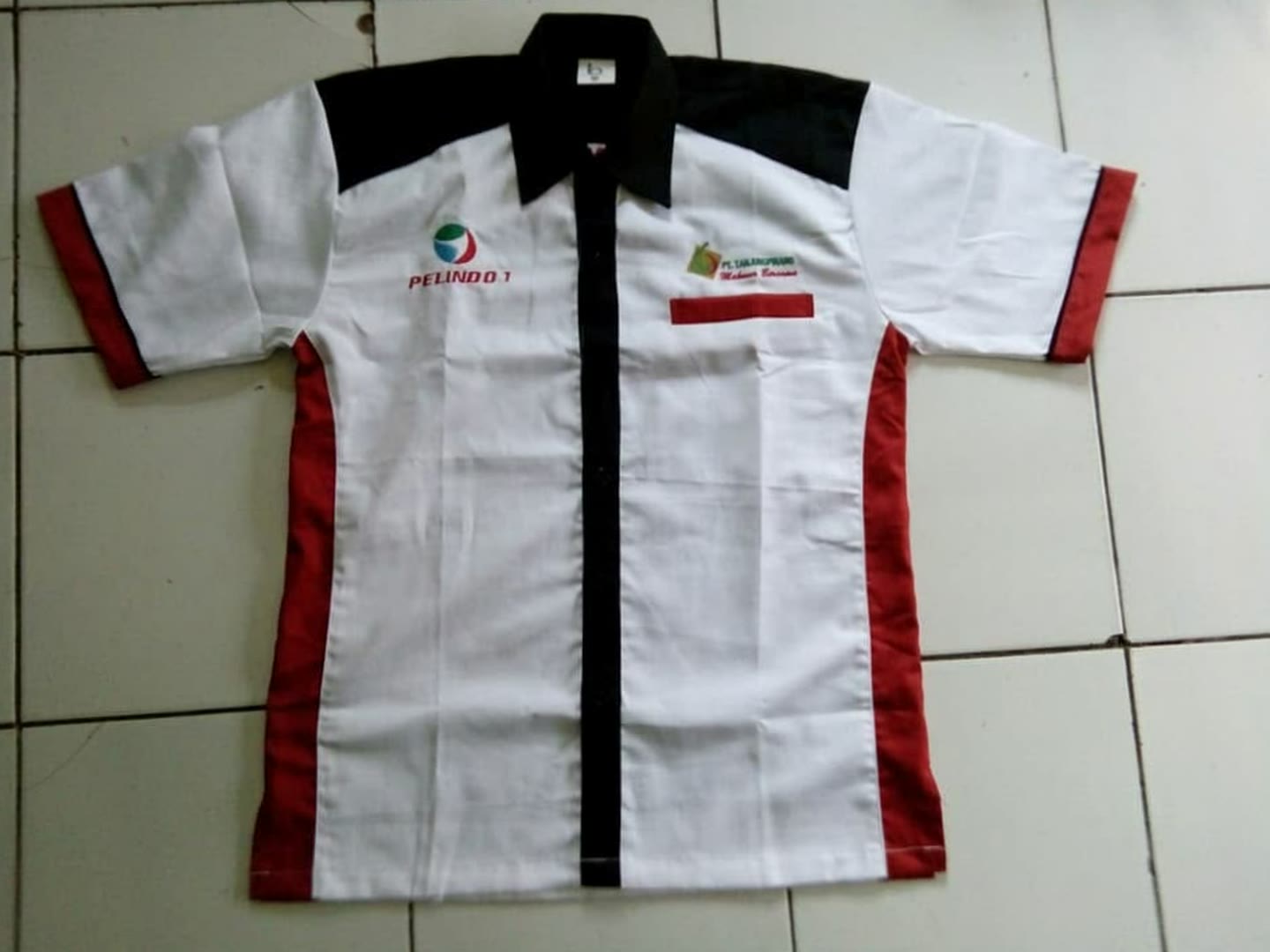 Kemeja lengan pendek putih dengan panel hitam dan merah.