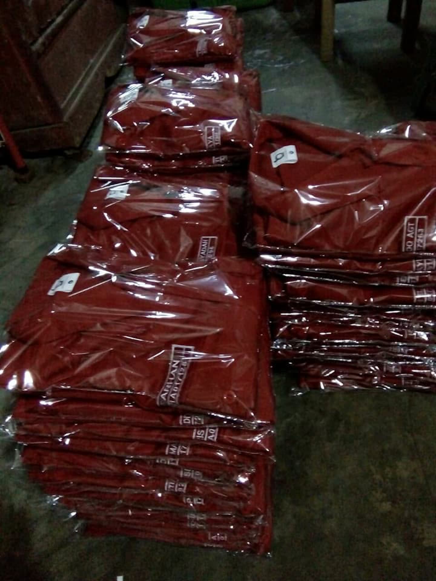 Tumpukan produk pakaian; sebagian terbungkus plastik. Jumlah pesanan dan kesiapan kirim tidak dapat dipastikan dari foto.
