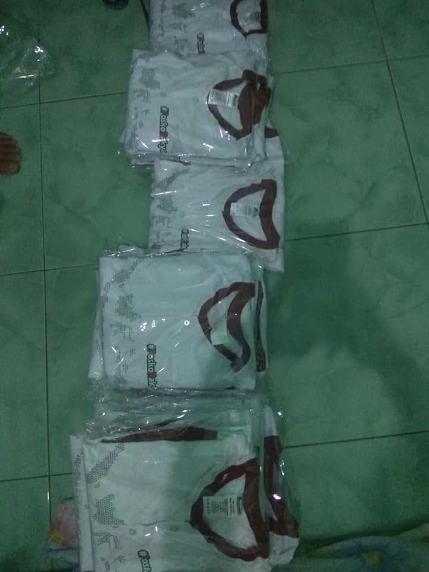 Tumpukan produk pakaian; sebagian terbungkus plastik. Jumlah pesanan dan kesiapan kirim tidak dapat dipastikan dari foto.