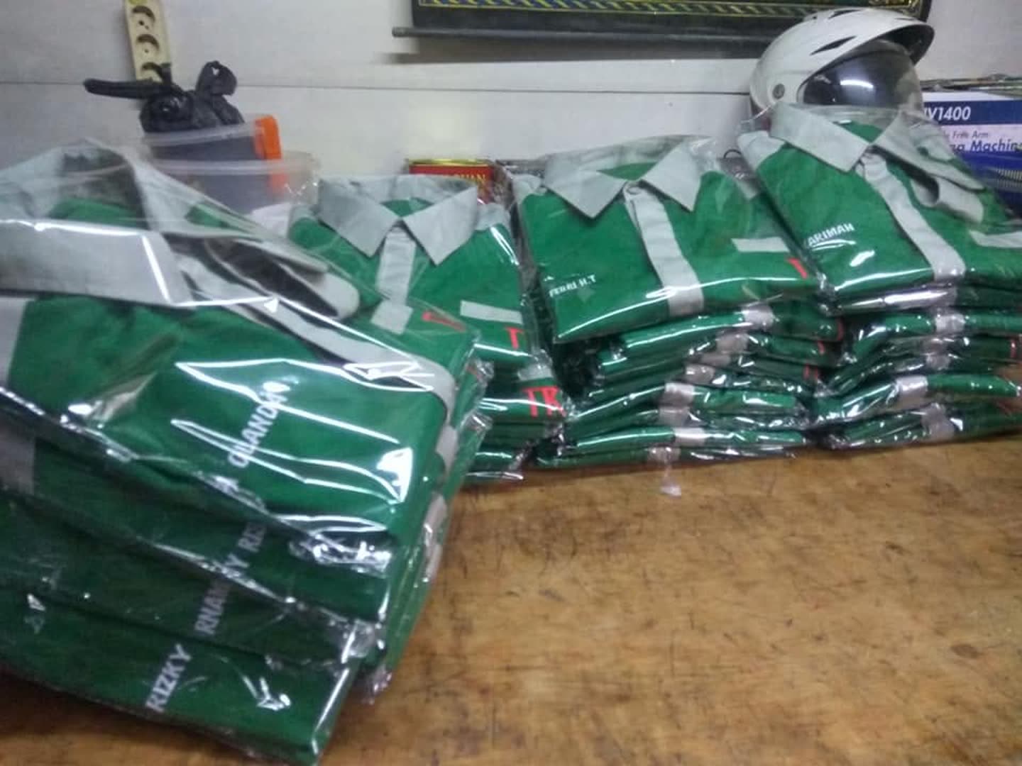Tumpukan produk pakaian; sebagian terbungkus plastik. Jumlah pesanan dan kesiapan kirim tidak dapat dipastikan dari foto.