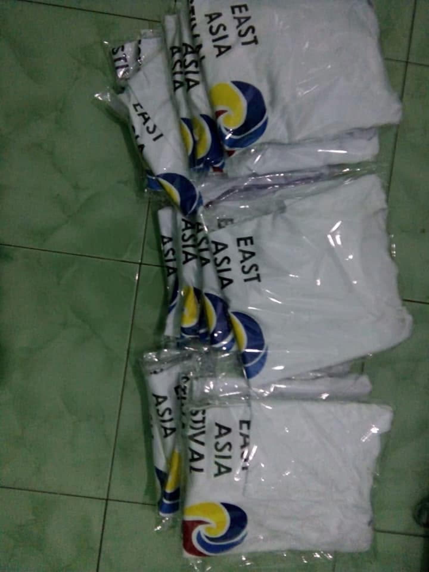 Tumpukan produk pakaian; sebagian terbungkus plastik. Jumlah pesanan dan kesiapan kirim tidak dapat dipastikan dari foto.