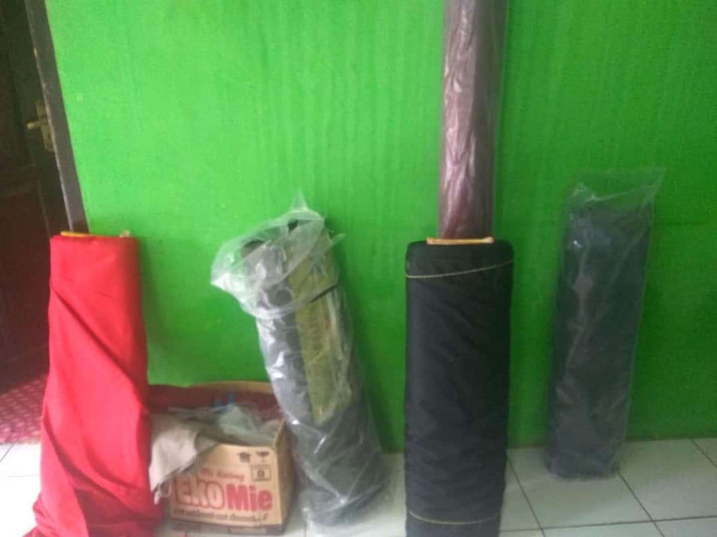 Beberapa gulungan kain berdiri; jenis serat dan merek belum diketahui.