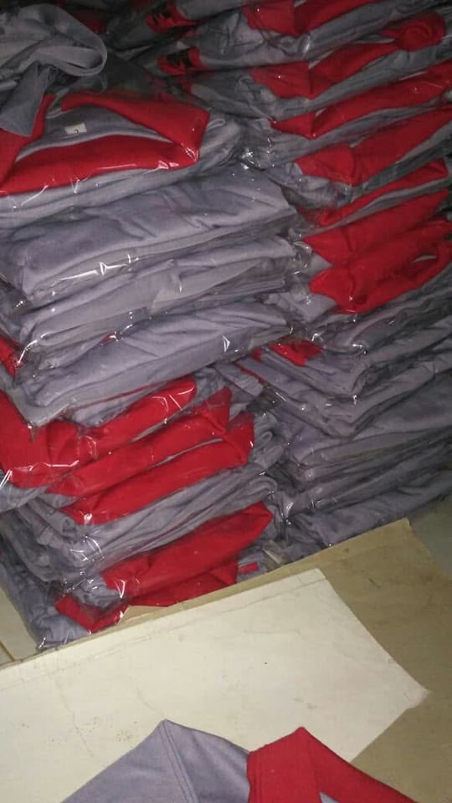 Tumpukan produk pakaian; sebagian terbungkus plastik. Jumlah pesanan dan kesiapan kirim tidak dapat dipastikan dari foto.