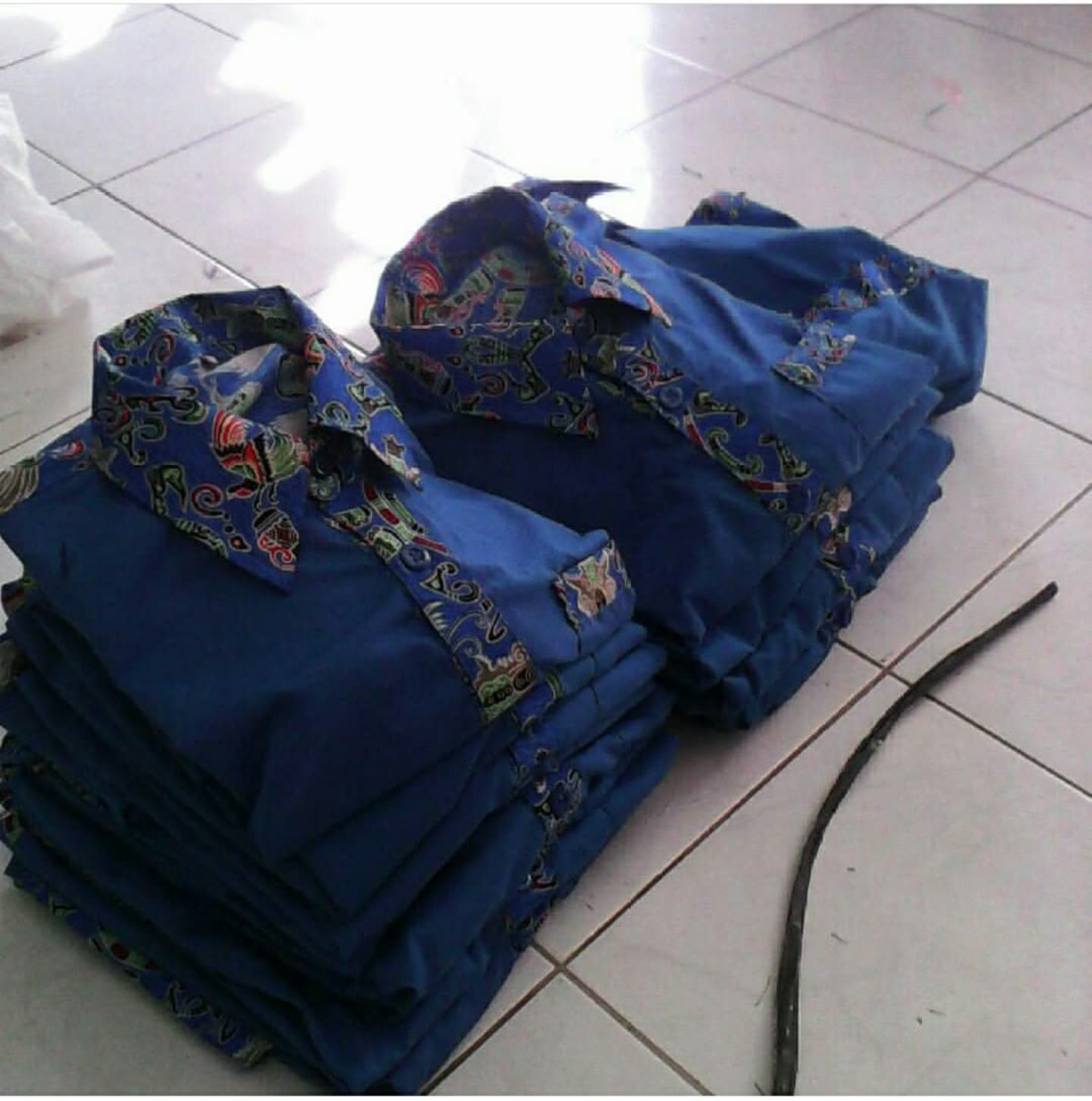 Tumpukan kemeja biru dengan panel kain bermotif.