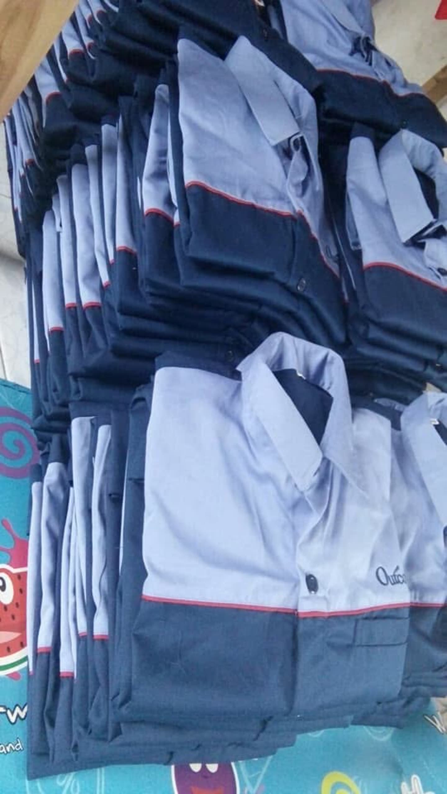 Tumpukan produk pakaian; sebagian terbungkus plastik. Jumlah pesanan dan kesiapan kirim tidak dapat dipastikan dari foto.