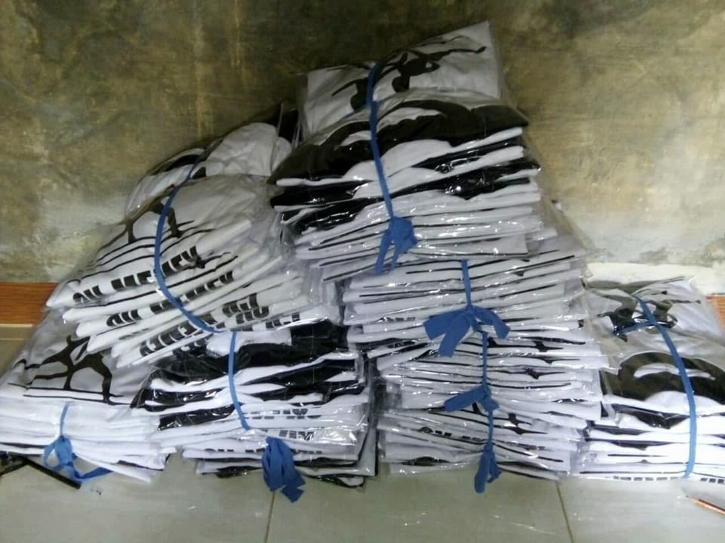 Tumpukan produk pakaian; sebagian terbungkus plastik. Jumlah pesanan dan kesiapan kirim tidak dapat dipastikan dari foto.