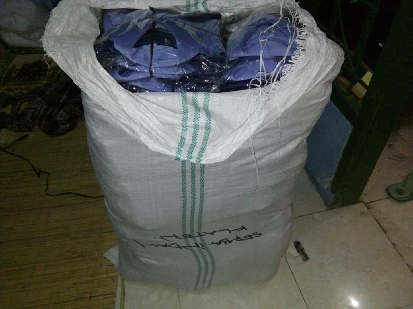 Tumpukan produk pakaian; sebagian terbungkus plastik. Jumlah pesanan dan kesiapan kirim tidak dapat dipastikan dari foto.