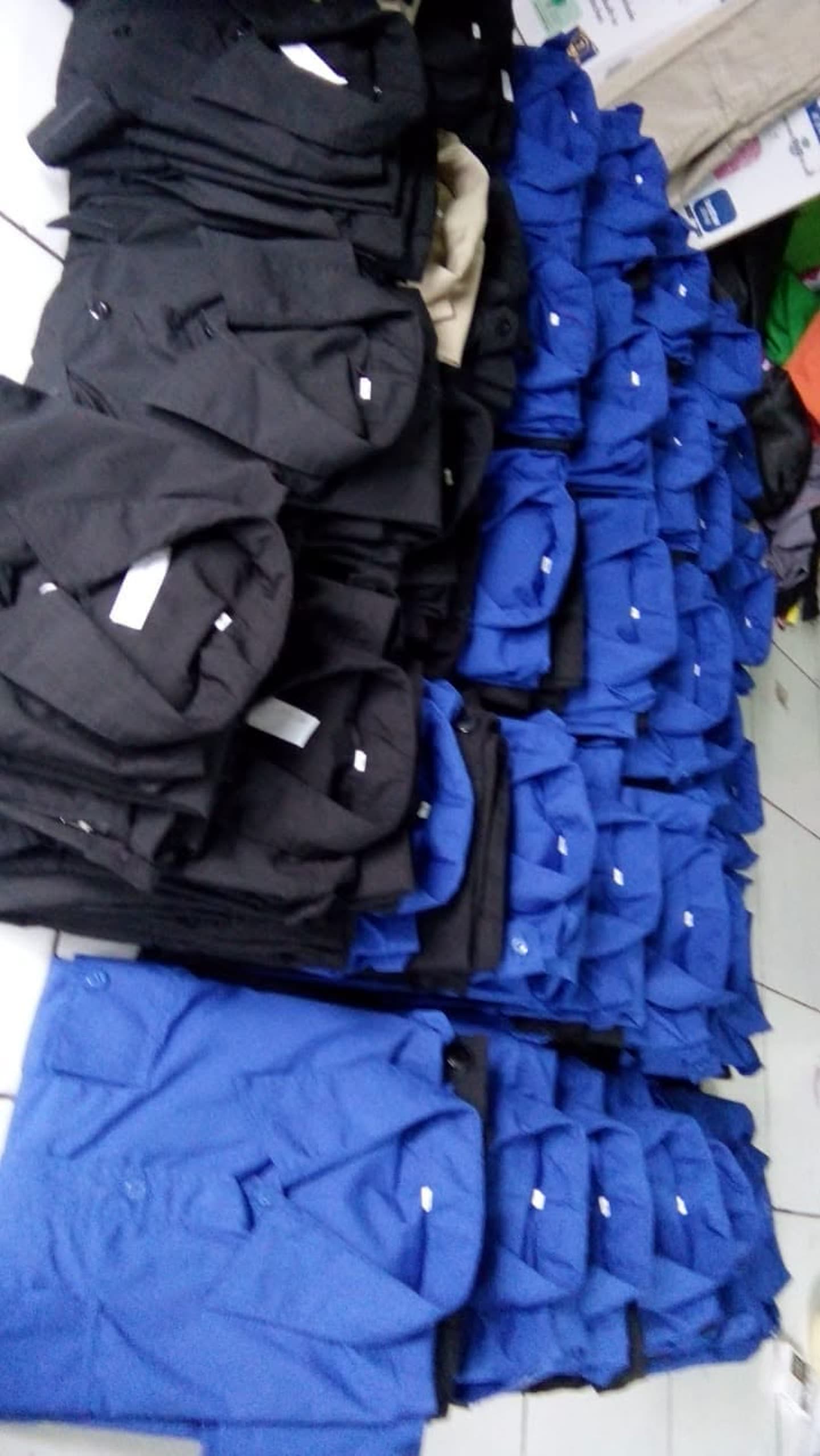 Tumpukan kemeja hitam dan biru dengan saku.