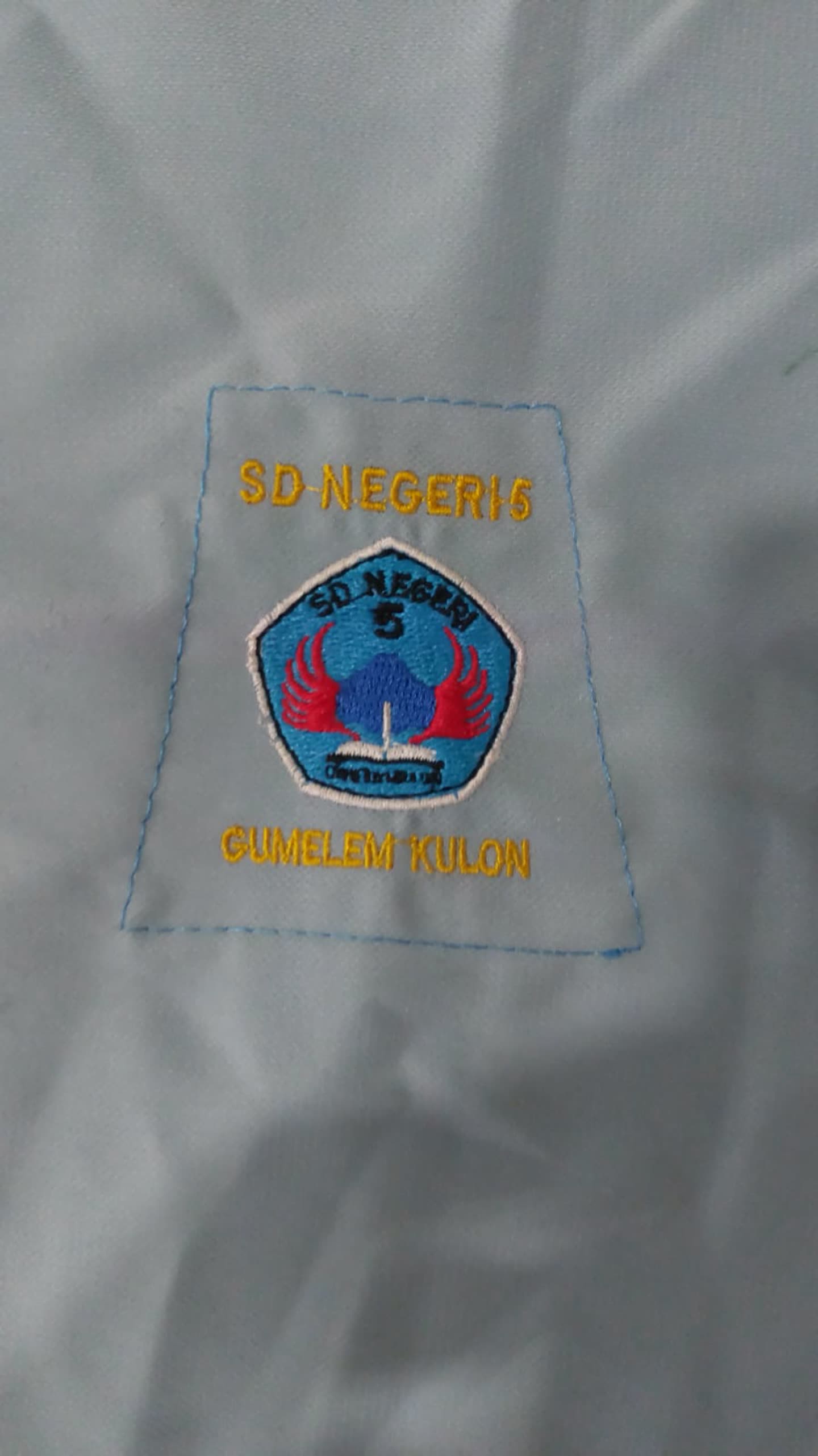 Bordir logo dan tulisan pada kain putih.