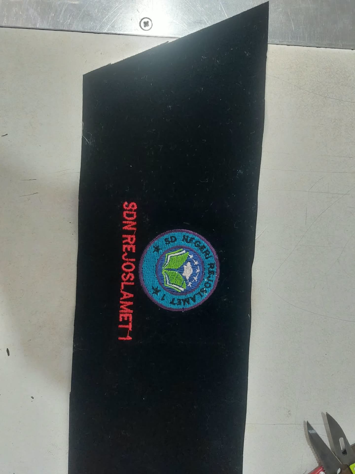 Logo bundar dan tulisan di potongan kain hitam.