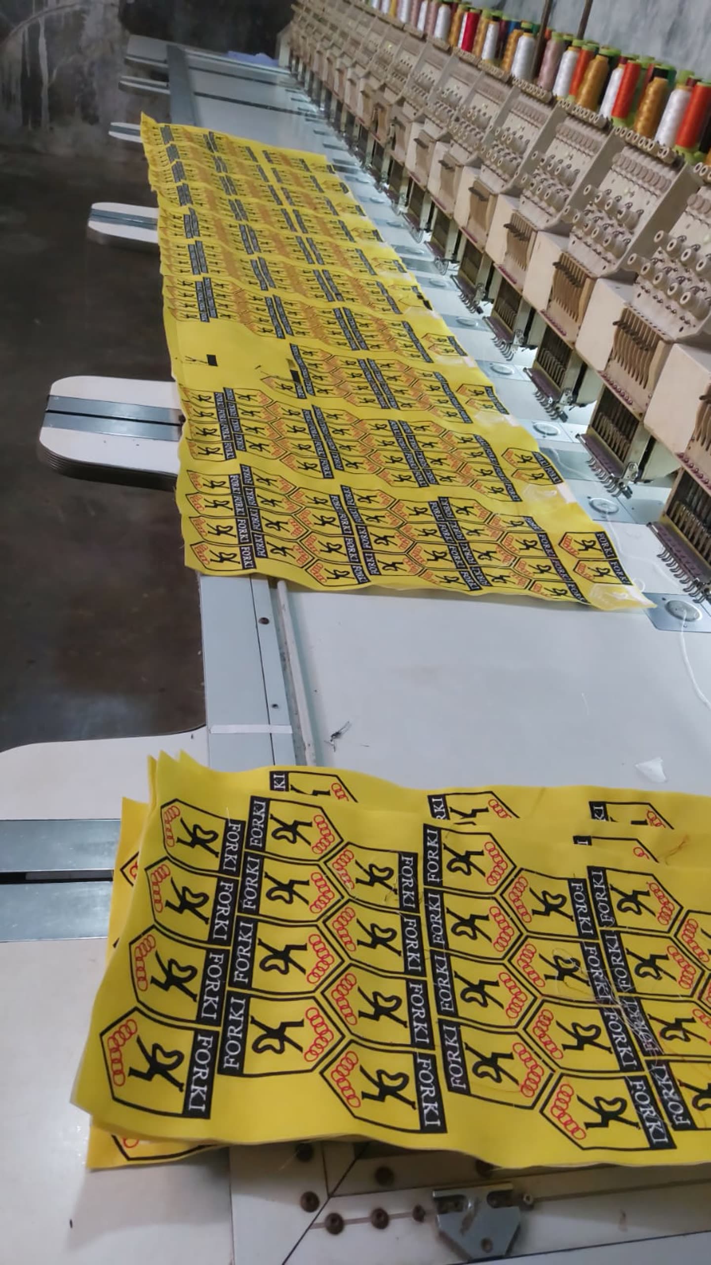 Lembaran bordir label kuning di mesin banyak kepala.