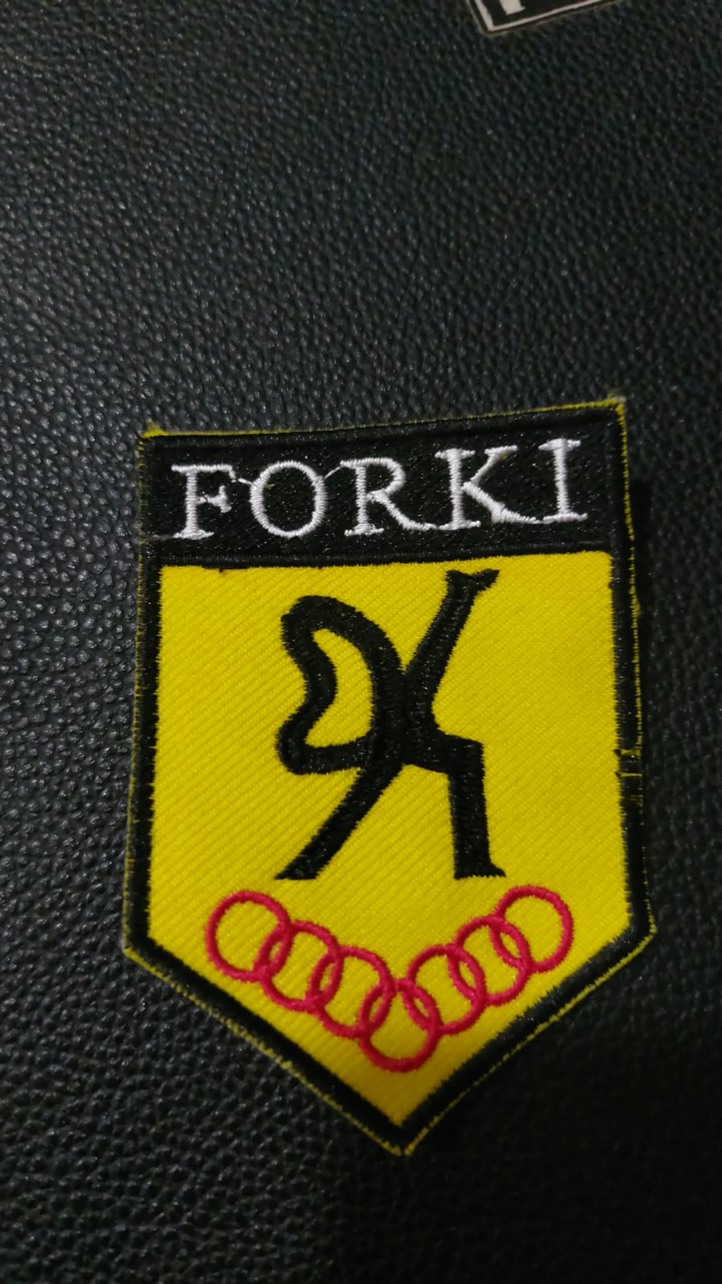 Emblem berbentuk perisai di kain hitam.