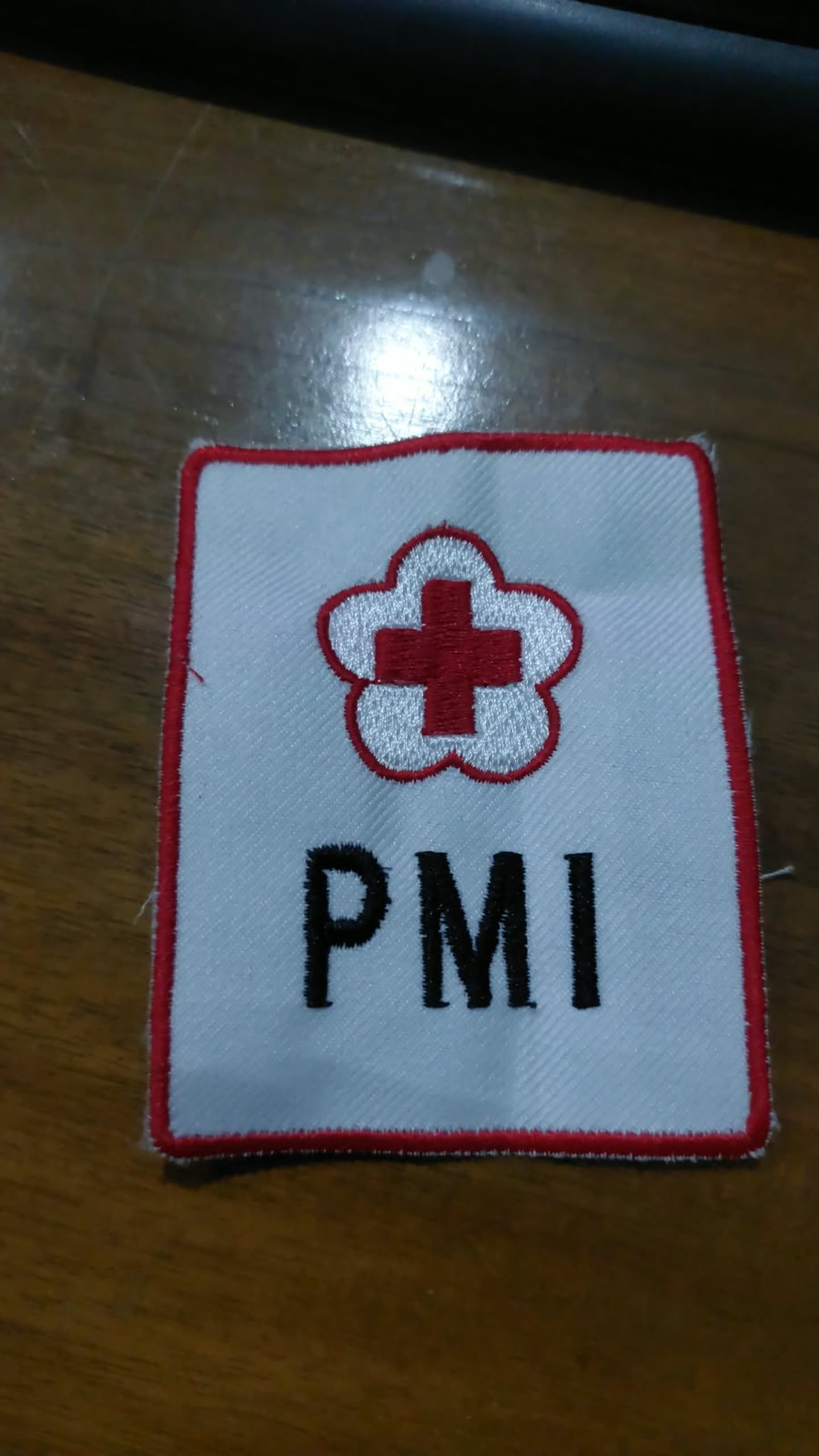 Patch putih dengan simbol dan tulisan merah.